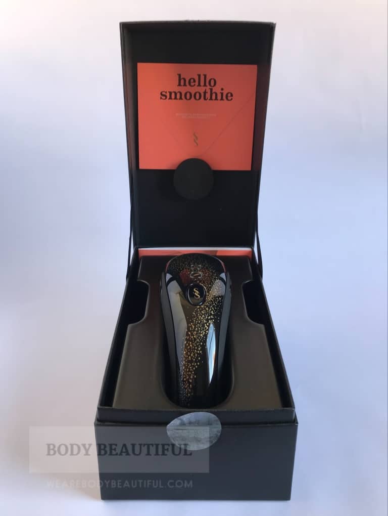 photo of the open lid box with the black and speckled-gold Muse IPL device resting in a plastic cradle and the striking orange 'hello smoothie' support programme invitation.