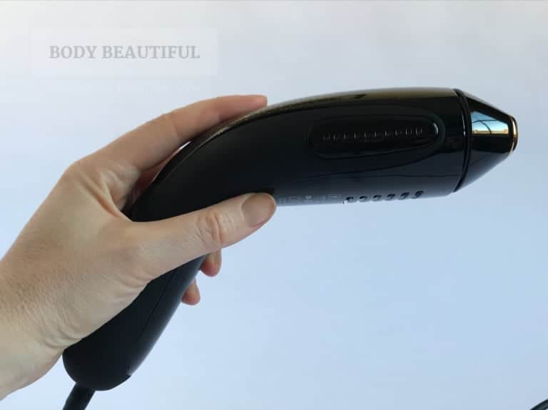 Photo of a hand gripping the Muse with the index finger naturally resting on the flash button (just a bit above of the curved handle). 