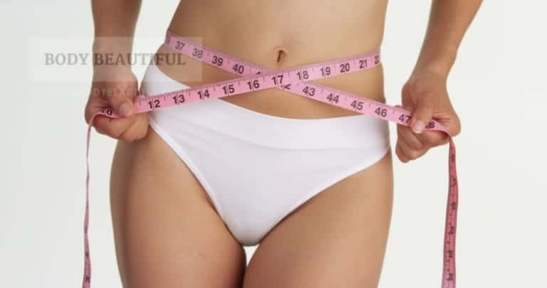 Photo of a lady's midriff wrapped with a pink tape measure showing shes very slim indeed.
