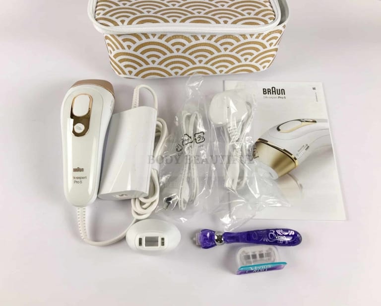 The contents of the Braun Pro 5 IPL kit laid out next to the white and gold wave-patterned storage case.