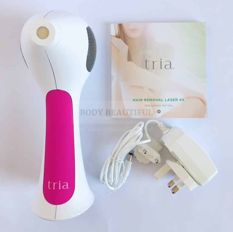 The fuschia Tria 4X laser, mains charging cable, and small square user manual.