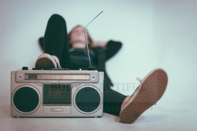 A person laying listening to an old school radio box.