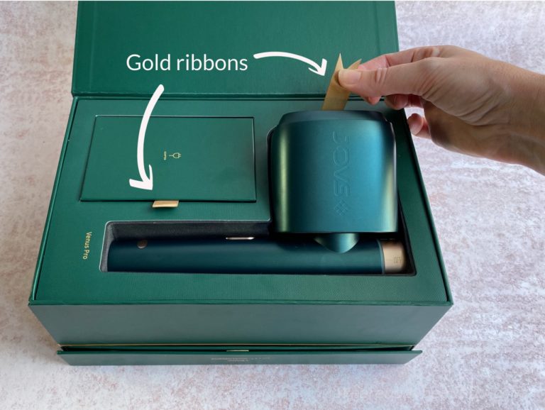 The packaging includes thoughtful touches like gold ribbons to lift the device from the foam bed, and looped ribbon tabs to open draws and lift lids.