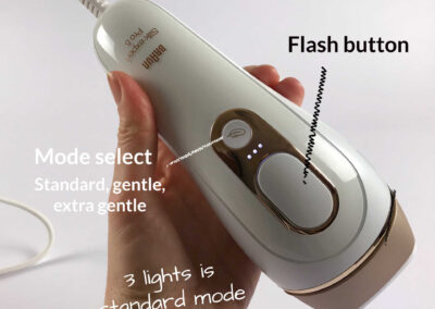 The Pro 5 IPL held in my hand showing the large flash button on top, and next to that the 3 small white LED lights showing it's in standard power mode, with the mode select button next to it. there are 3 modes, standard, gentle and extra gentle.